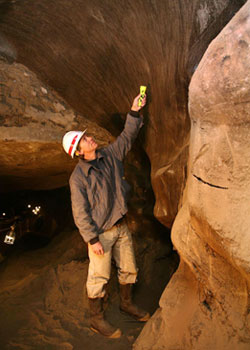 Man pointing to an ice wedge in the tunnel's Winze section.