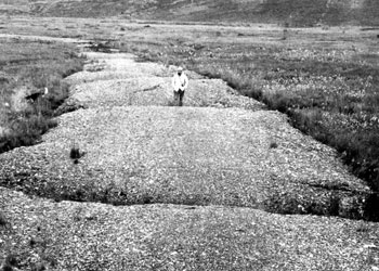 Photo depicting a gravel road damaged by the thawing of ice wedges.
